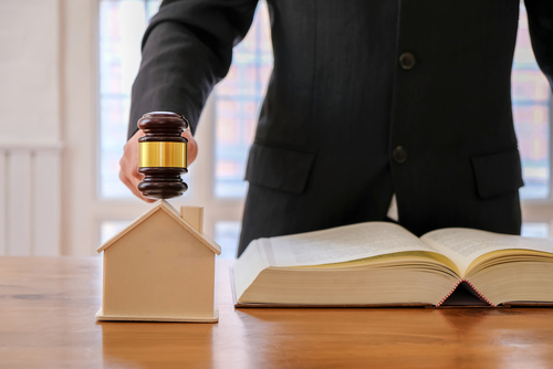 Image Of Lawyer Holding A Auction Hammer On Model House - Caliber Home Loans – Mortgage Modification Attorney in Queens, New York
